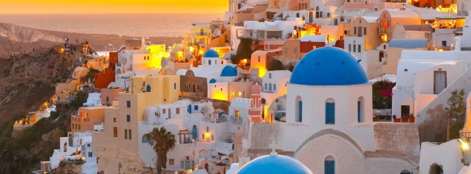 Santorini hillside at sunset with white buildings and blue domes